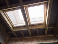 Crew carefully installing a skylight, sunlight streaming through the opening.