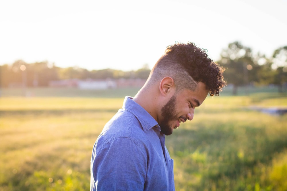 man in blue polo shirt standing on green grass field during daytime