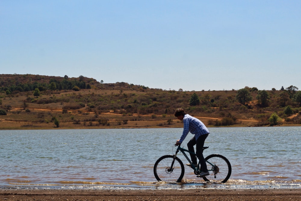 man in white shirt riding bicycle on beach during daytime