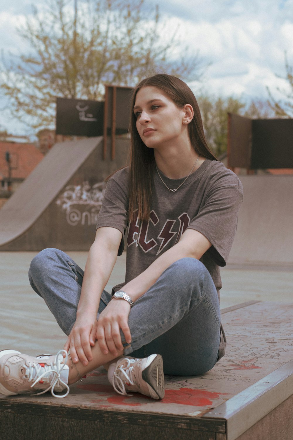 woman in gray crew neck t-shirt and gray denim jeans sitting on gray concrete floor