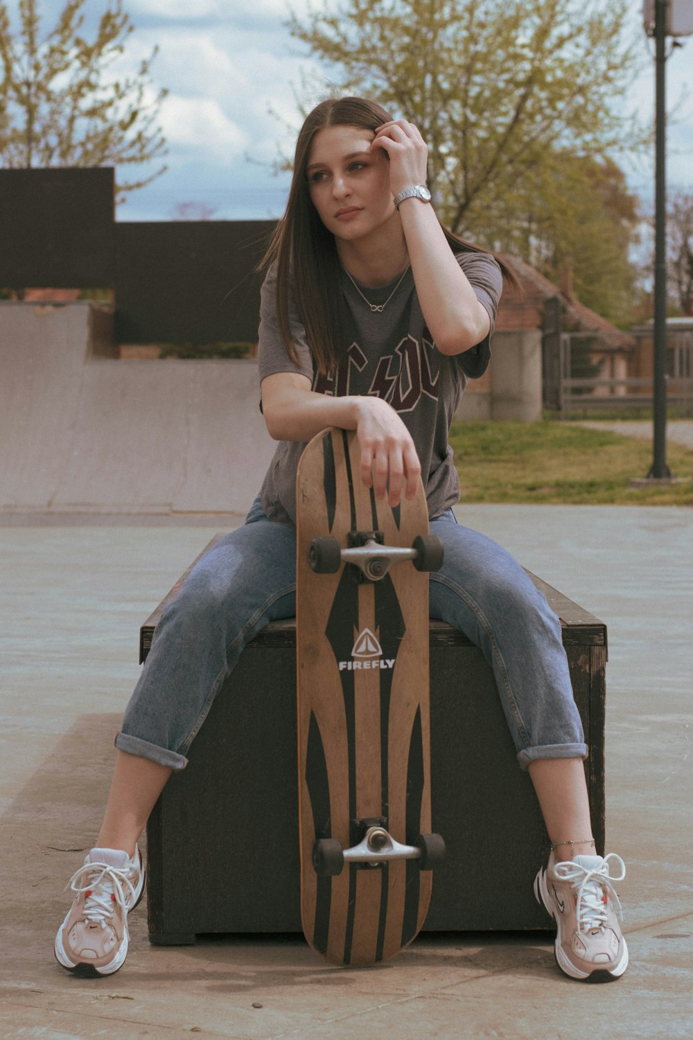 woman in black and white adidas hoodie and blue denim jeans sitting on brown wooden chair