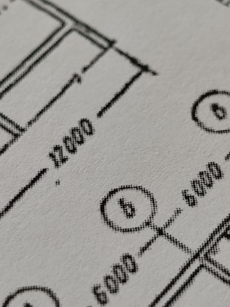 Close-up of engineers analyzing technical blueprints in an industrial setting.