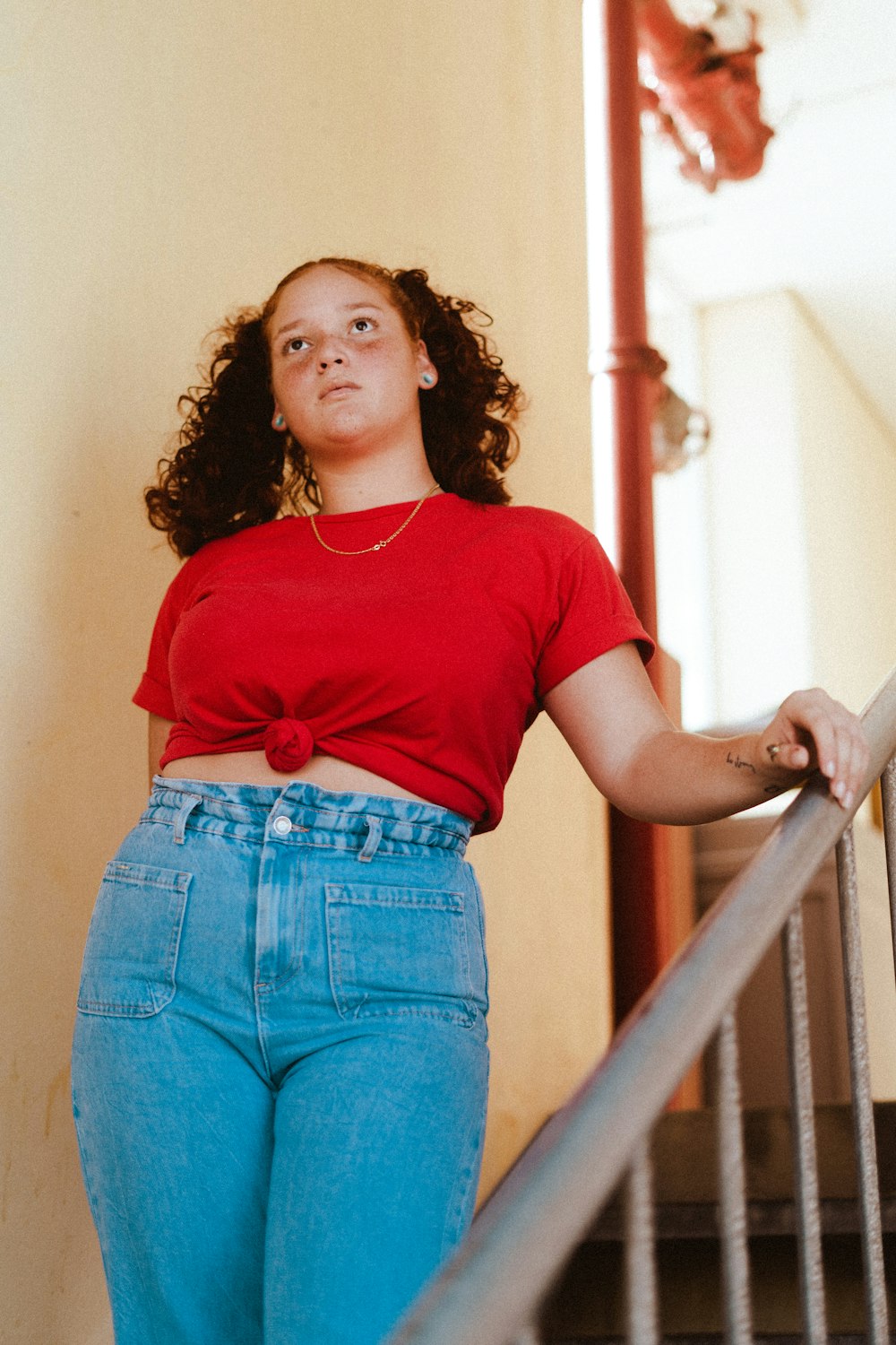 woman in red crew neck t-shirt and blue denim shorts standing on brown wooden staircase