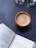 A cup of coffee rests on a dark wooden surface, next to an open book displaying poetry. Small white flowers are visible in the background, adding a delicate touch.