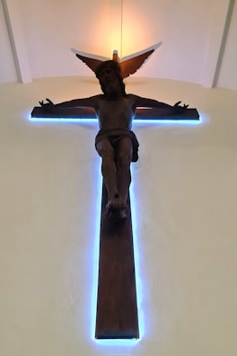 A serene digital illustration of a glowing cross against a soft baby blue background.