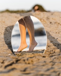 woman in white leather pumps standing on brown sand during daytime