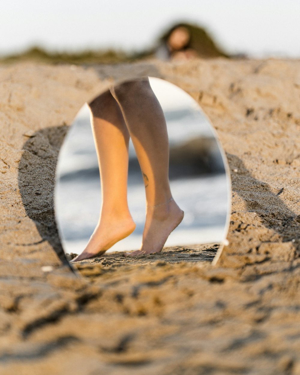 woman in white leather pumps standing on brown sand during daytime