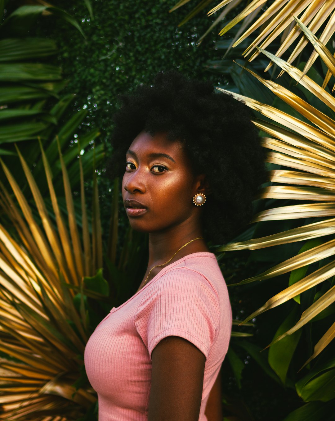 woman in pink scoop neck shirt standing beside green palm plant