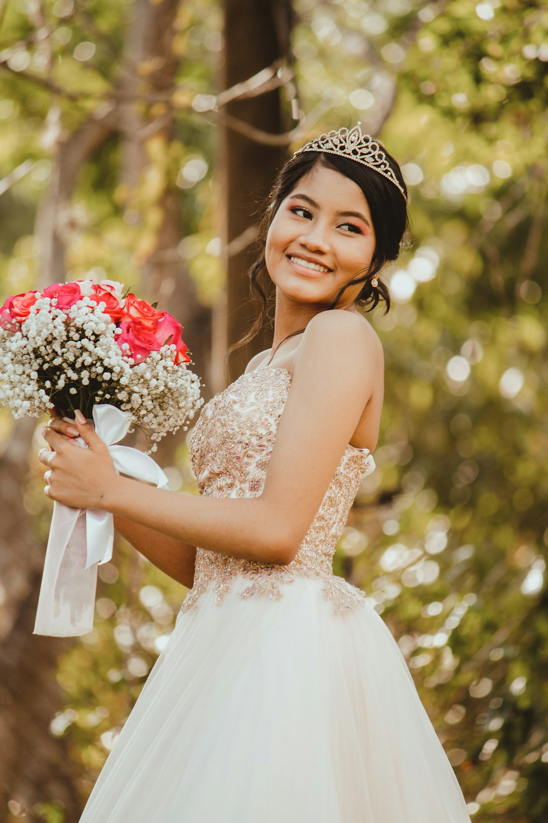 woman in white floral dress holding bouquet of red roses