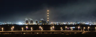 A power generation facility glowing under evening lights, showcasing complex infrastructure.
