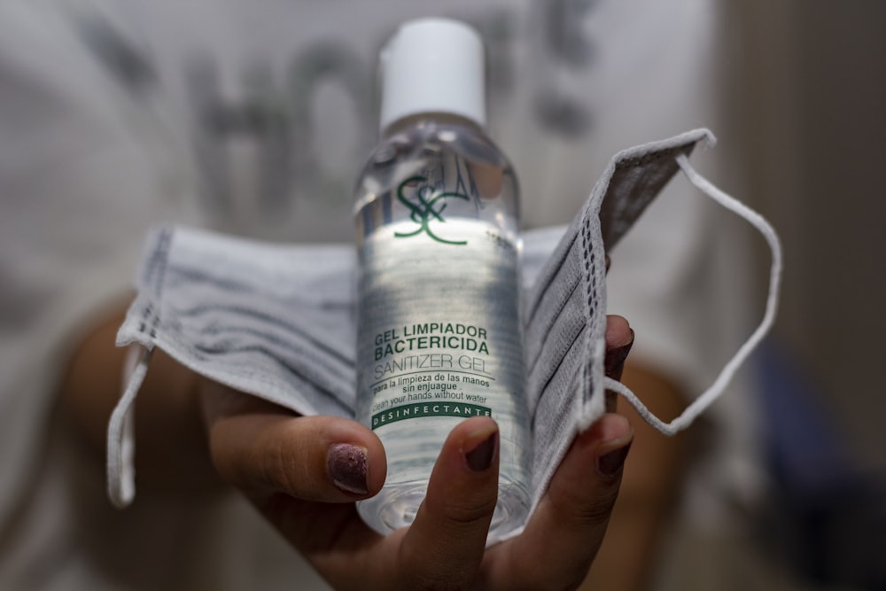 person holding white and green labeled plastic bottle