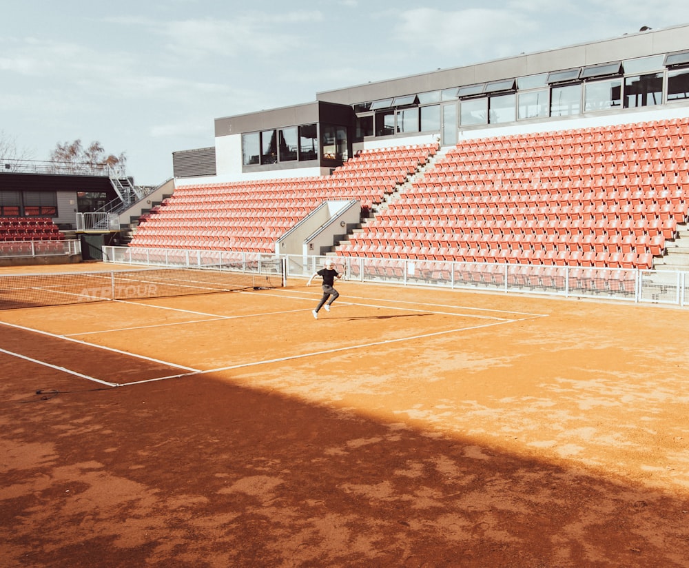 man in black shirt and pants playing basketball on track field during daytime