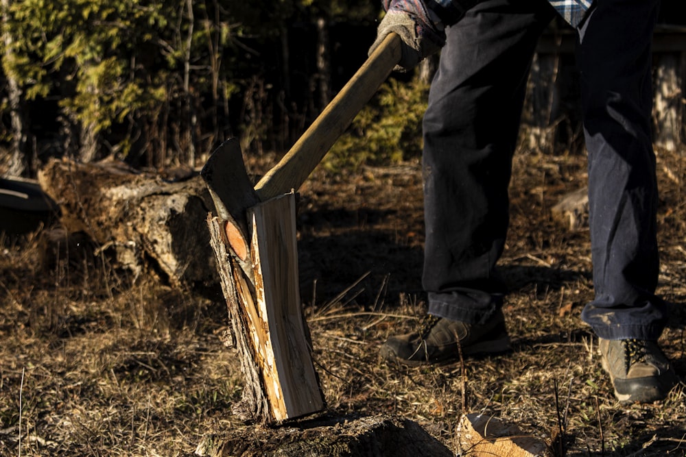 Persona in giacca nera e pantaloni che tiene bastone di legno marrone