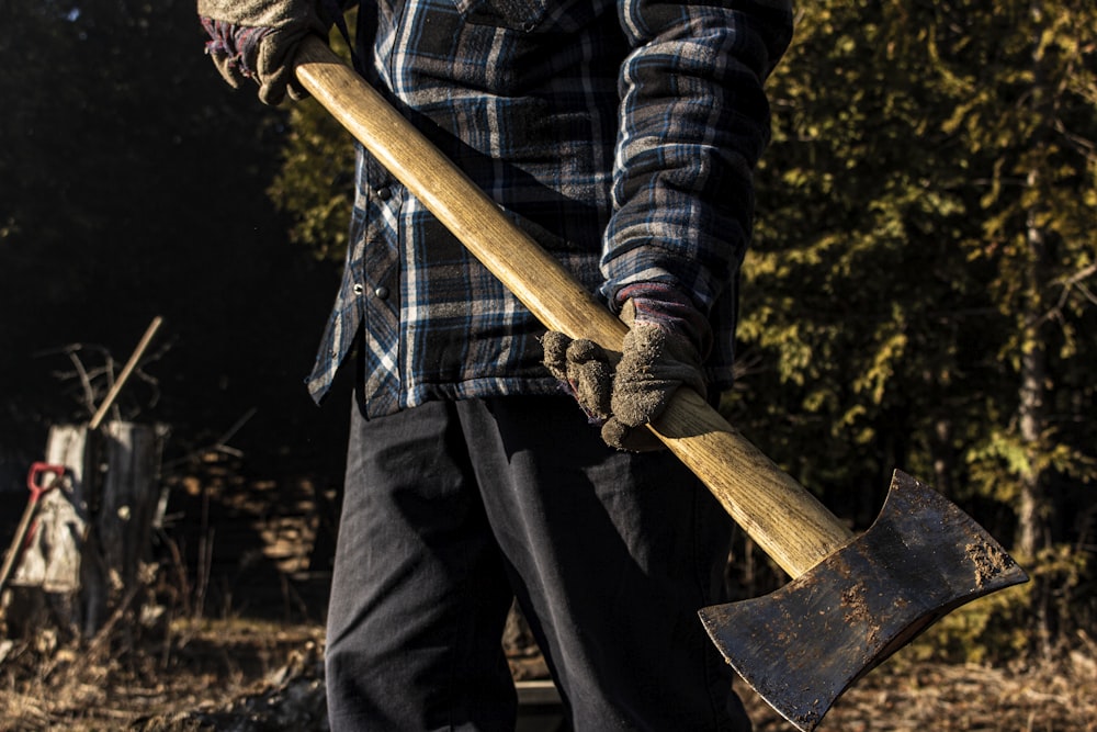 person in black and white plaid long sleeve shirt holding brown wooden stick