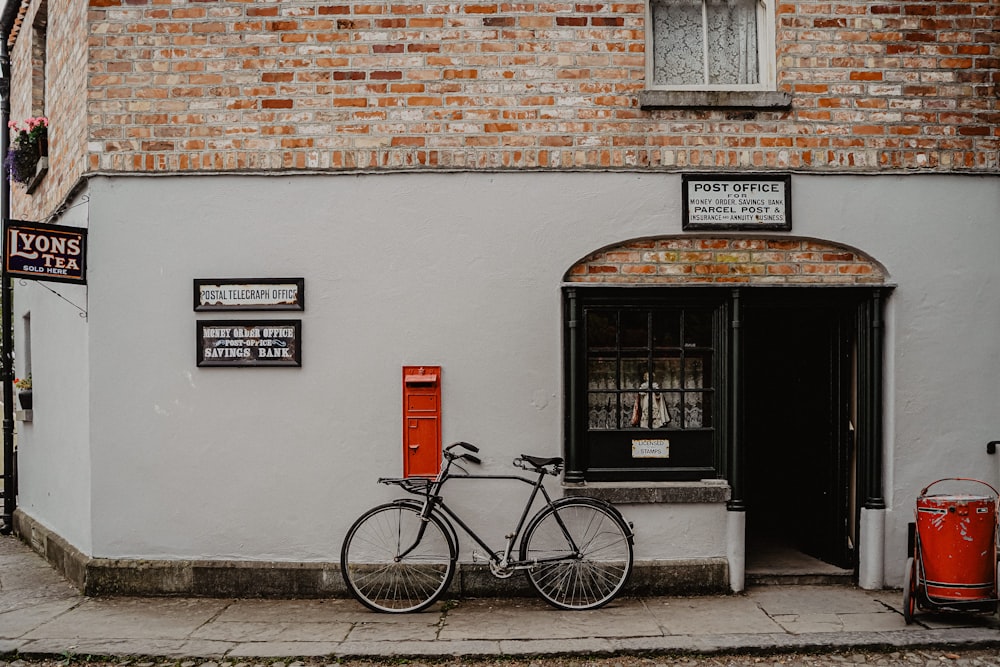 black city bike parked beside brown brick building