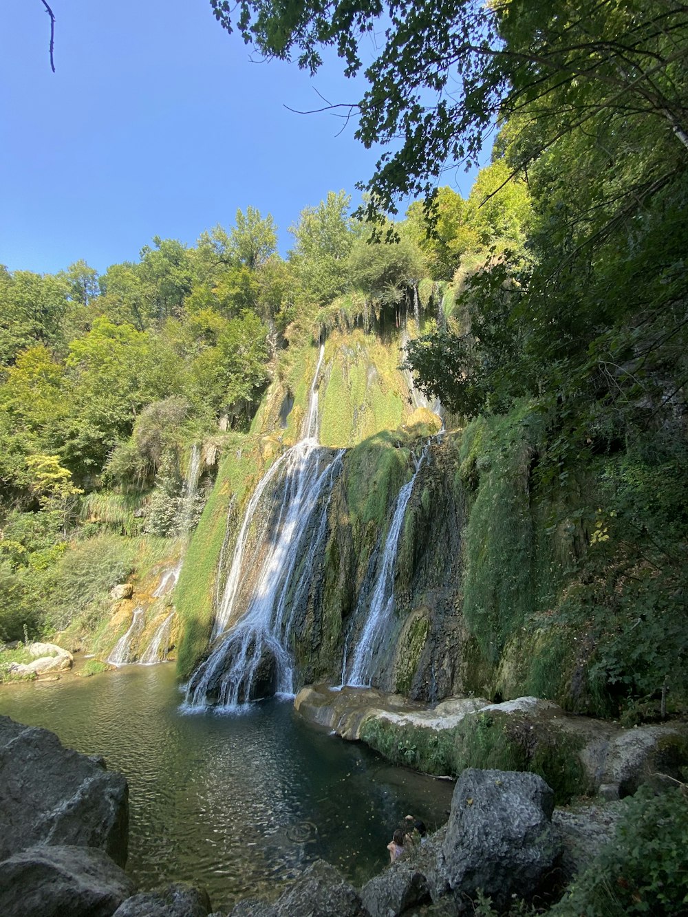 waterfalls in the middle of green trees during daytime