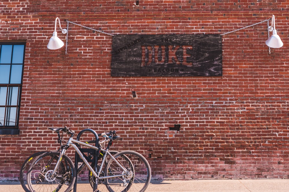 black and white bicycle parked beside brown brick wall