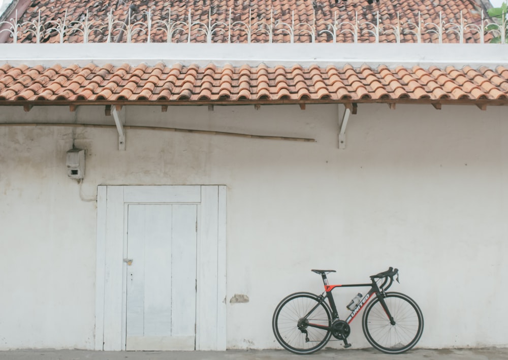 red and black mountain bike parked beside white wooden door