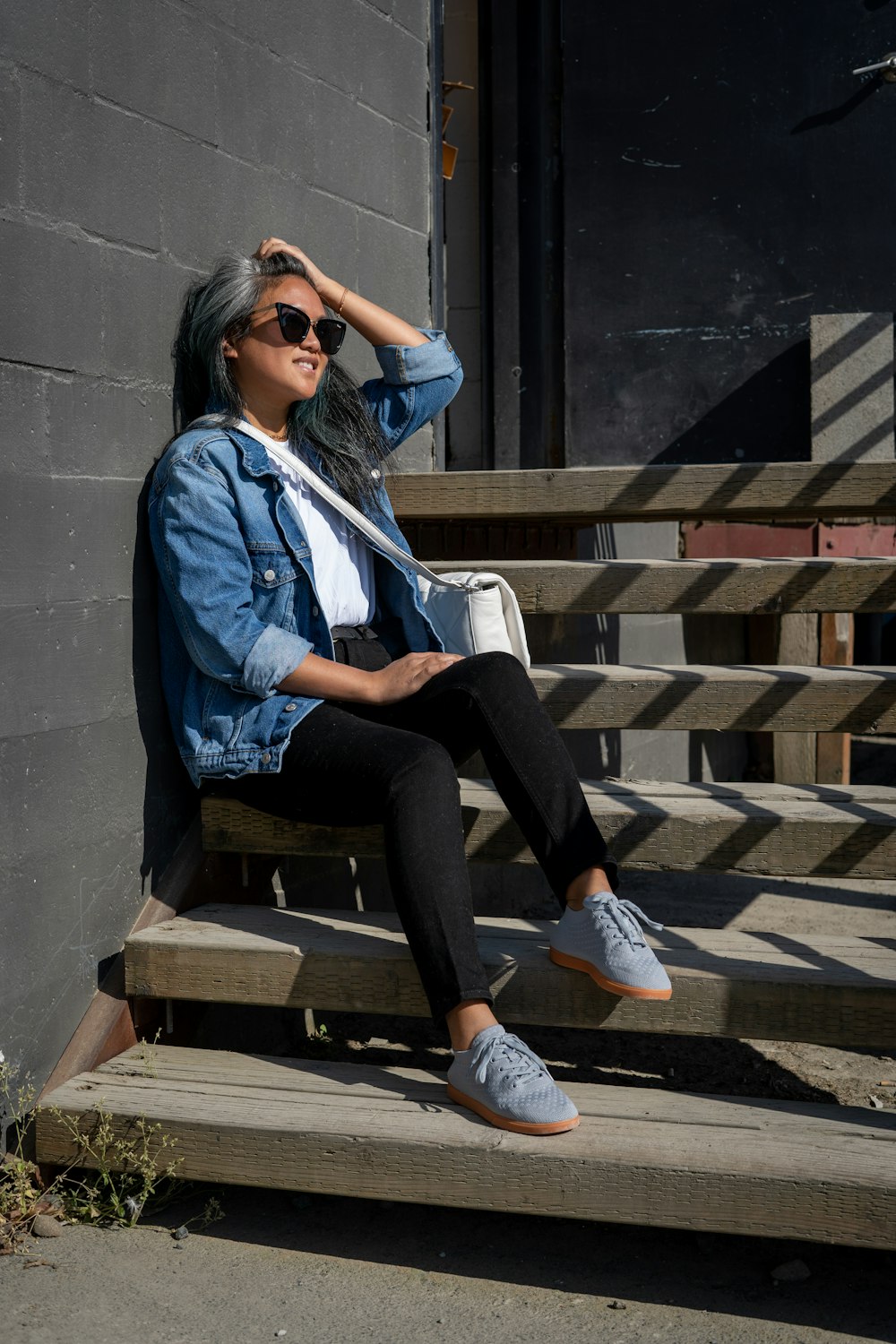 mulher na jaqueta azul e calças pretas sentadas no banco de madeira marrom