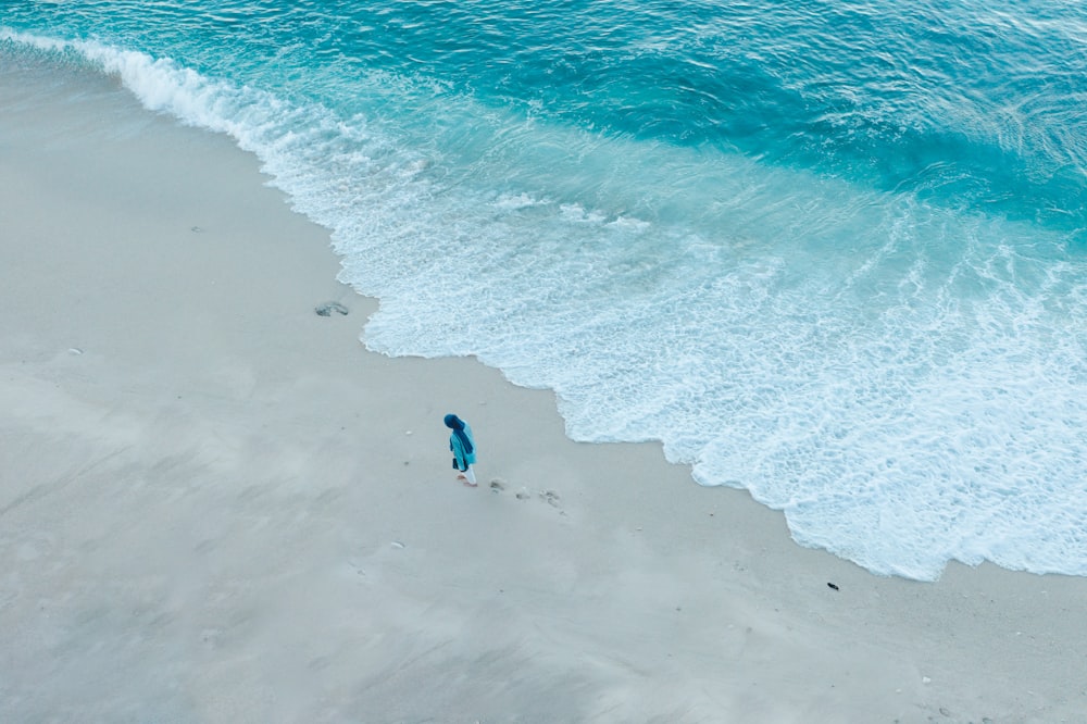 낮 동안 해변을 걷고 있는 파란 셔츠를 입은 사람