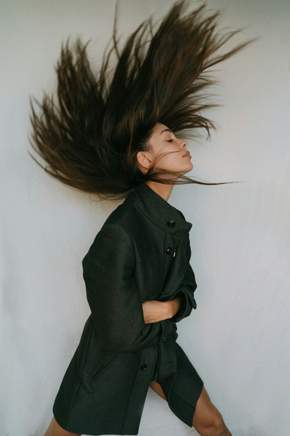 Mujer con abrigo negro sosteniendo su cabello