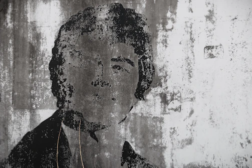 A striking black and white urban portrait capturing raw emotion against a textured city wall.