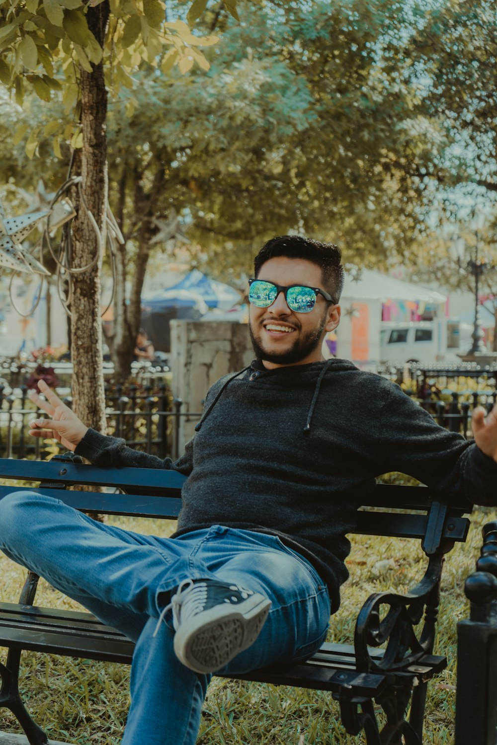 man in black sweater and blue denim jeans sitting on black metal bench during daytime