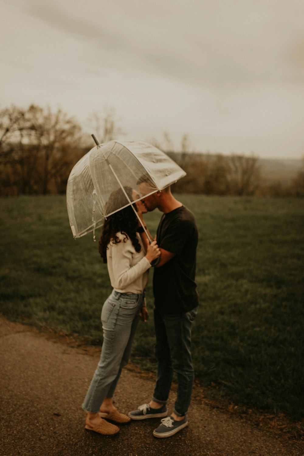 man and woman holding umbrella walking on green grass field during daytime
