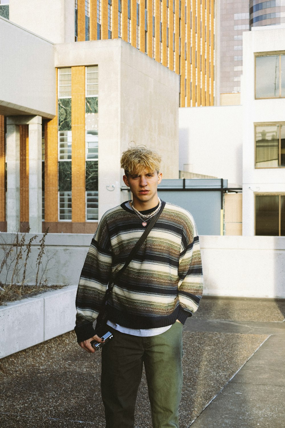 man in black and white striped sweater standing near white concrete building during daytime
