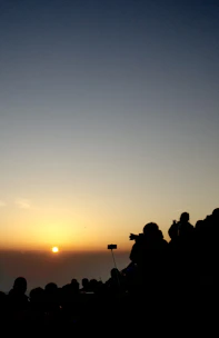 A vibrant group of travel creators capturing a sunrise over a serene mountain lake.