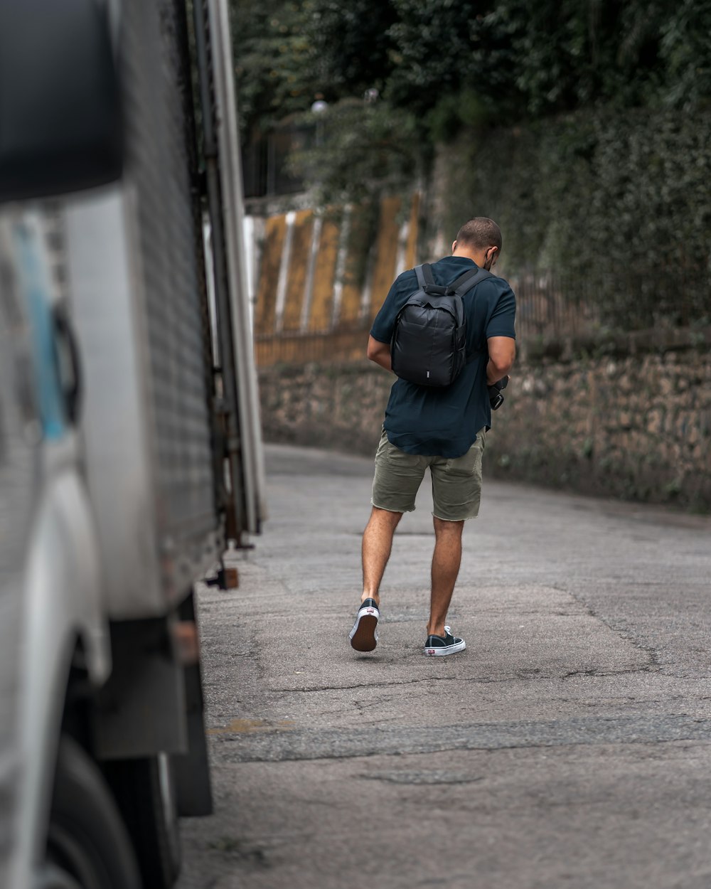 man in blue jacket and brown shorts walking on sidewalk during daytime