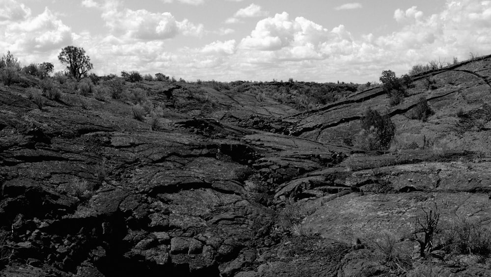 grayscale photo of rocky mountain under cloudy sky