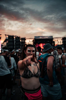 A dynamic shot of a young woman at a music festival wearing a colorful techno-inspired outfit with neon accessories.