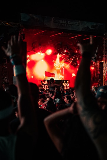 Crowd dancing under colorful lights at a nighttime music festival.