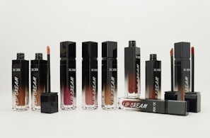 Flat lay of several lip balm holders in warm cream and black tones arranged neatly on a soft fabric.