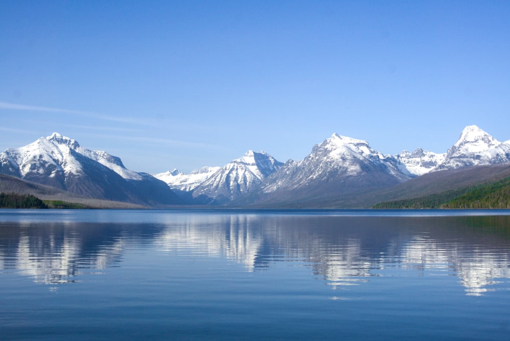 blue body of water near mountain under blue sky during daytime