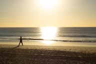 silhouette of person walking on beach during sunset