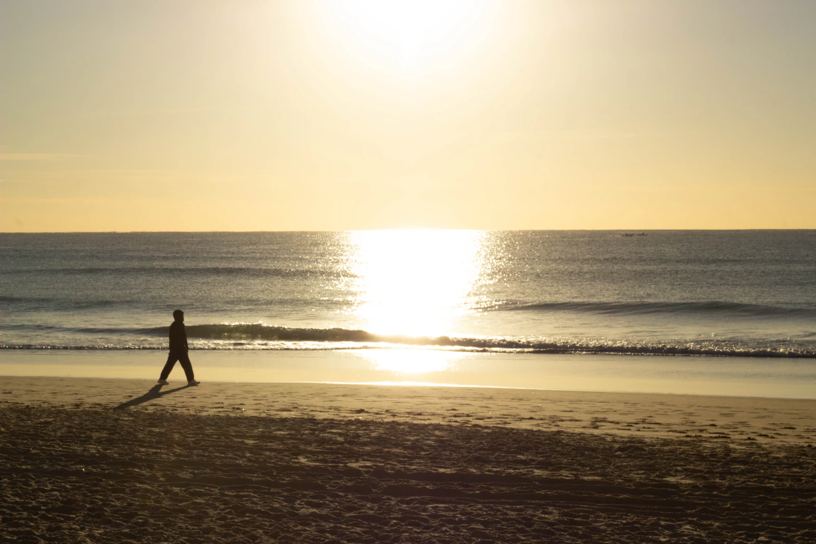 Silhouette of a person walking alone on a beach at sunset, symbolizing choosing silence and moving forward after a breakup