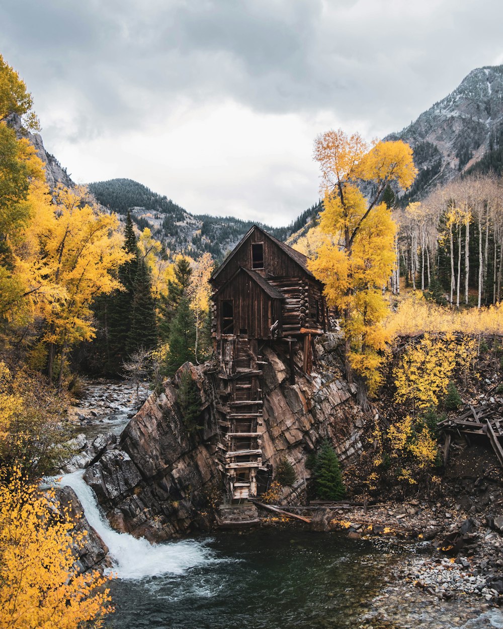 brown wooden house near river and trees during daytime