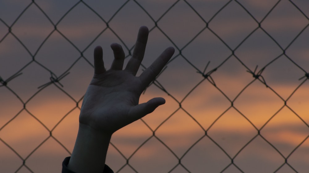 persons left hand on black metal fence