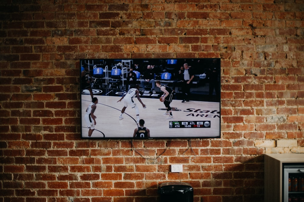 TV de tela plana preta montada na parede de tijolos marrons