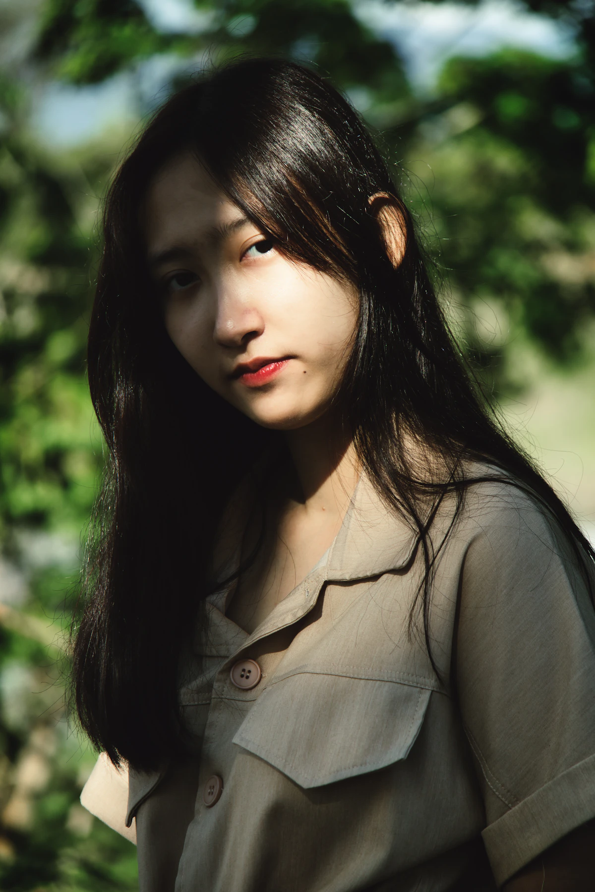 Asian creative director in a brown blazer beside greenery