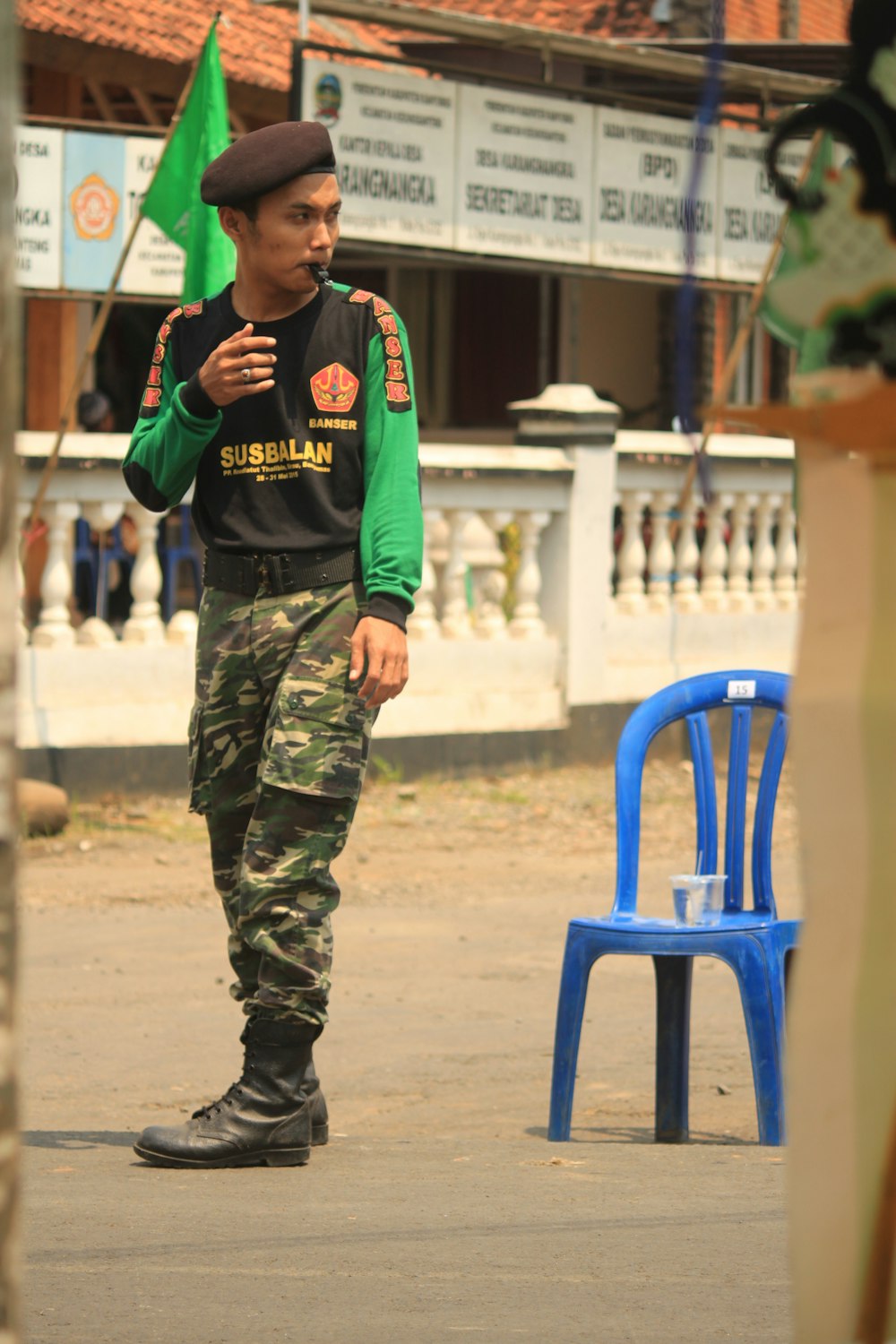 man in green and black camouflage pants and blue shirt holding a phone