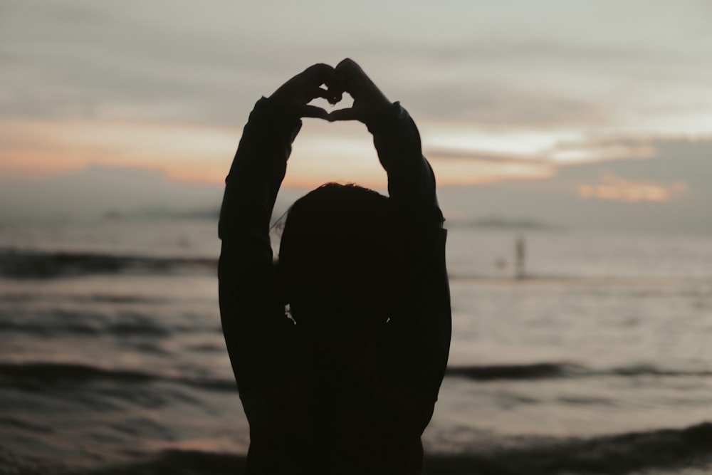 silhouette of persons hand forming heart