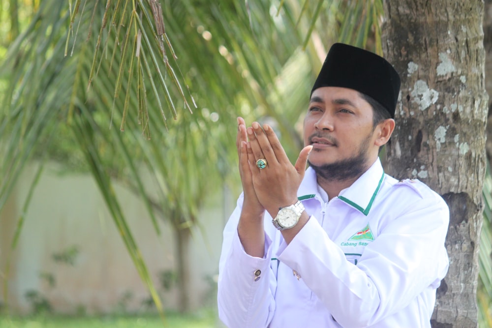 man in white dress shirt and black hat holding green plant during daytime