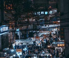 A bustling night market in Bangkok illuminated by colorful neon signs.