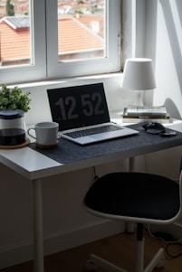 A minimalist workspace with a sleek laptop, notebook, and a cup of coffee, bathed in natural light.