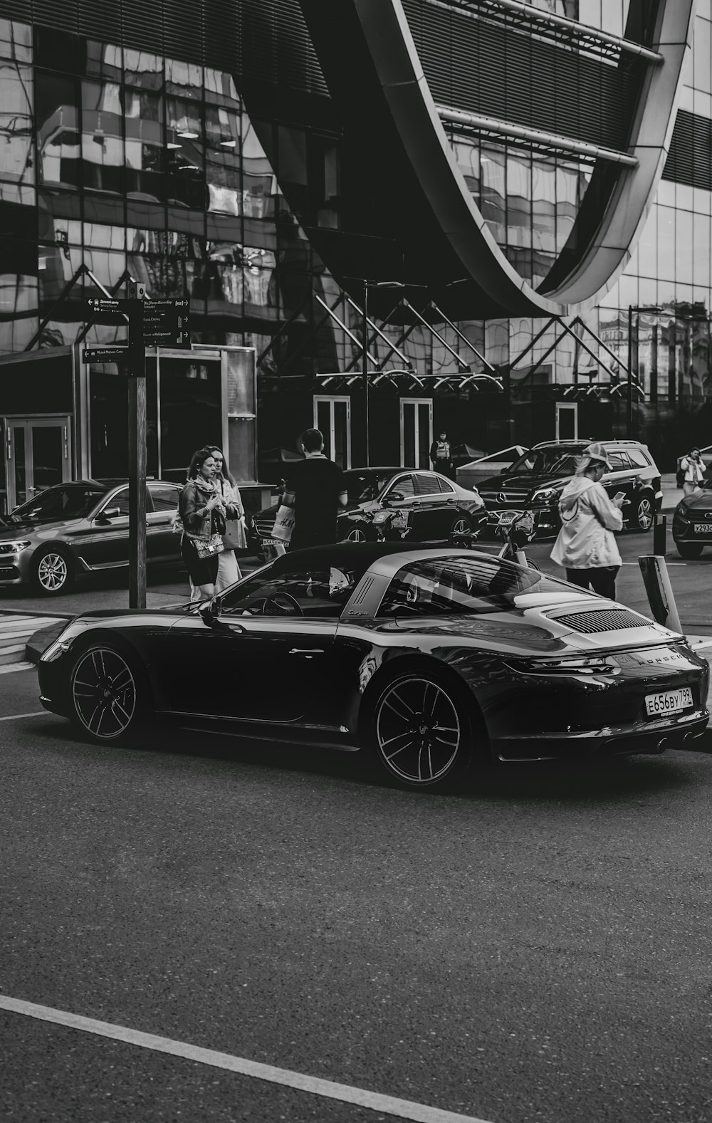 grayscale photo of man and woman riding on black convertible car