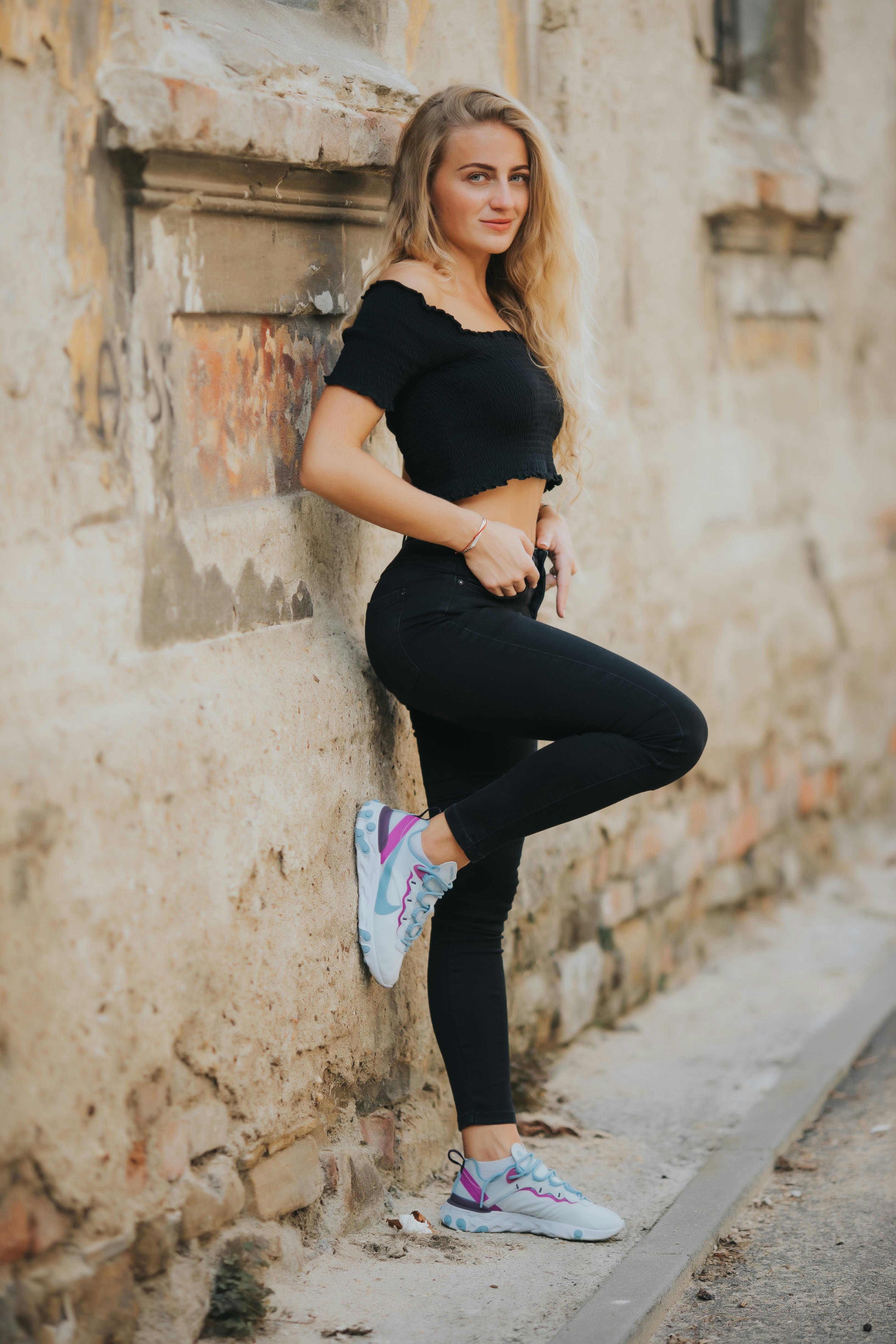 woman in black shirt and black pants sitting on concrete wall during daytime