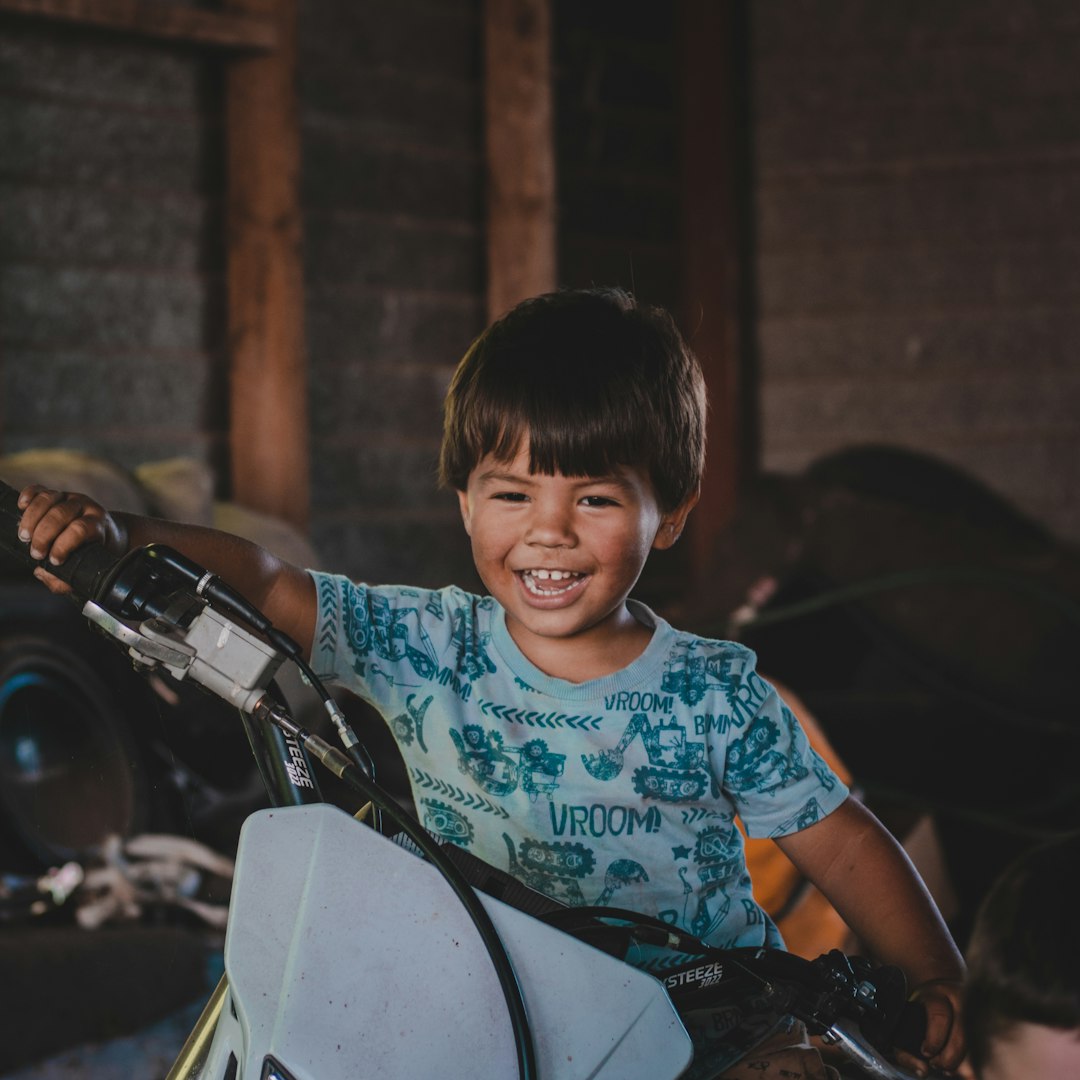 boy in blue and white crew neck t-shirt riding on motorcycle